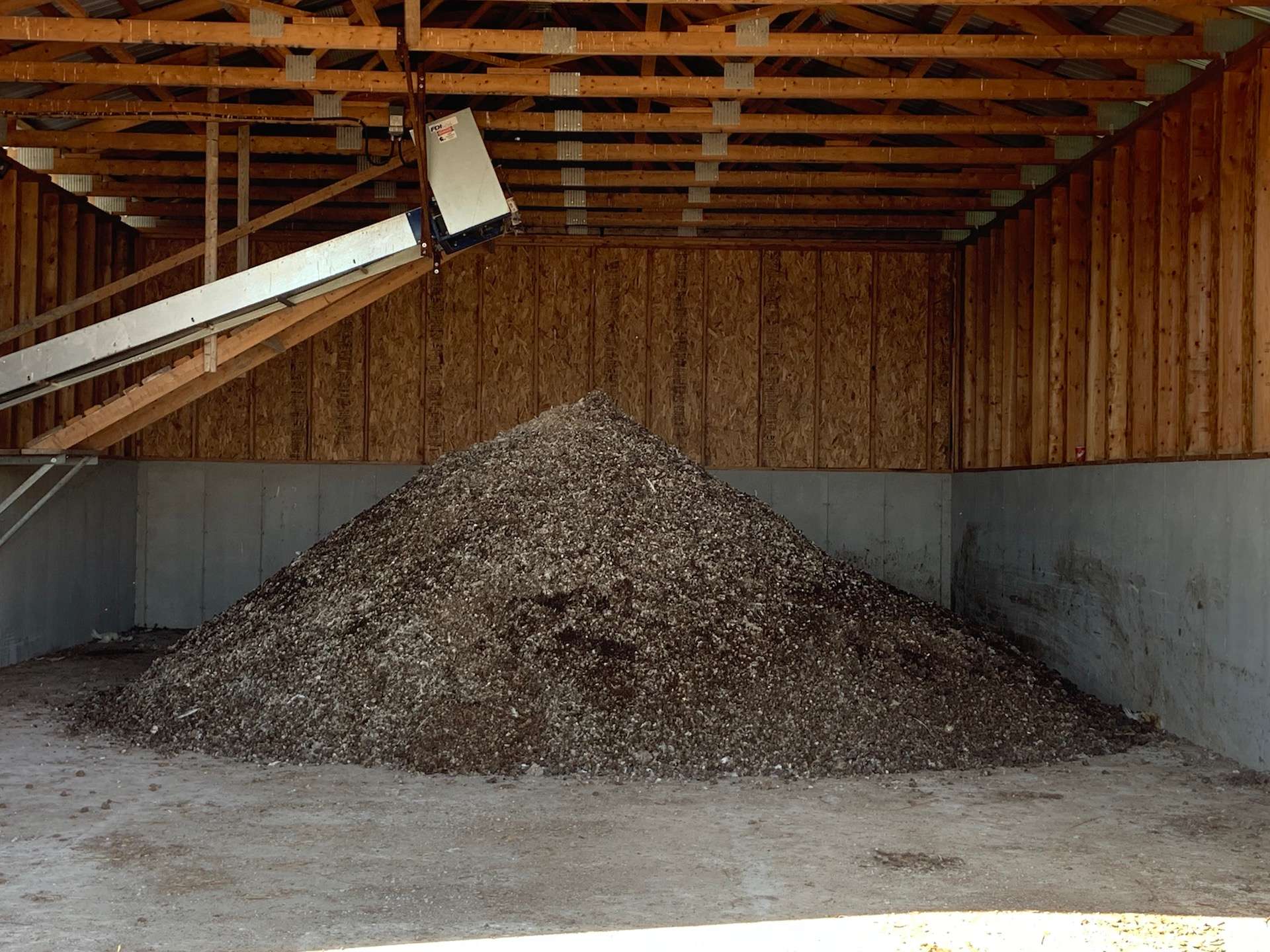 Manure pile inside a storage building fed by an FDI conveyor